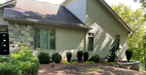 Modern residential house with stone and siding exterior, landscaped front with shrubs and mulch