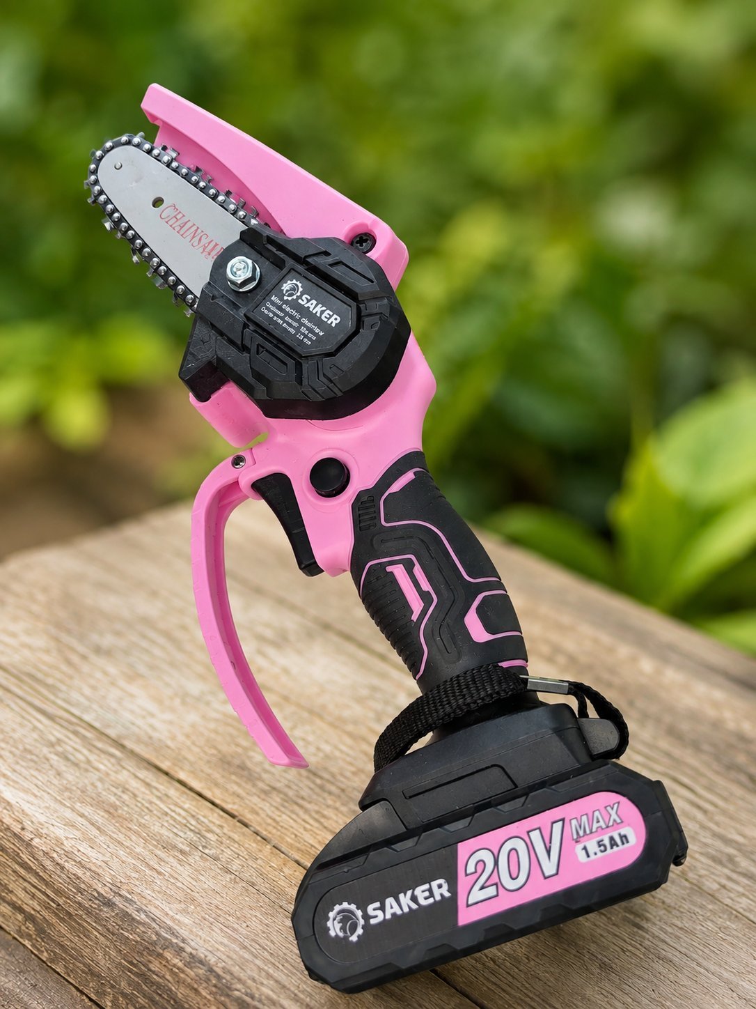 Pink and black cordless chainsaw with 20V battery attached, displayed on wooden surface with blurred green garden background