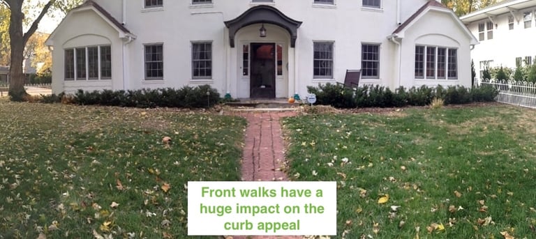 White house with brick front walkway and green lawn with fallen leaves, illustrating how front walkways impact curb appeal